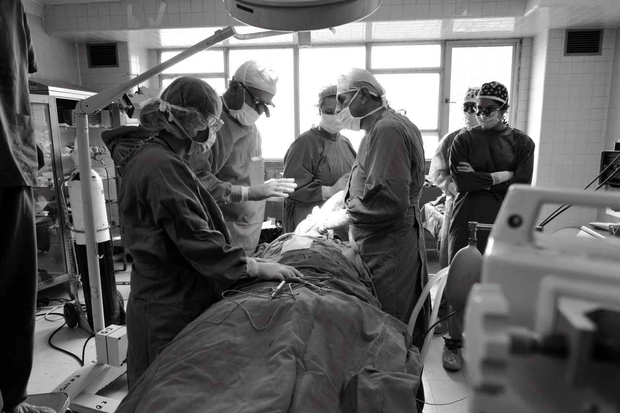 Black and white image of surgeons operating in a hospital setting, showcasing teamwork and precision.